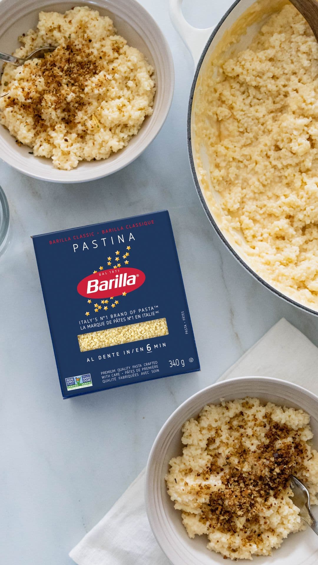 Un trio de bols remplis de pâtes pastina, chacun garni de fromage crémeux et d’une bonne cuillerée de beurre, le tout présenté sur une toile de fond simple. | US_PROD-Npa2zgZIpcqFuZBrOB3Ye